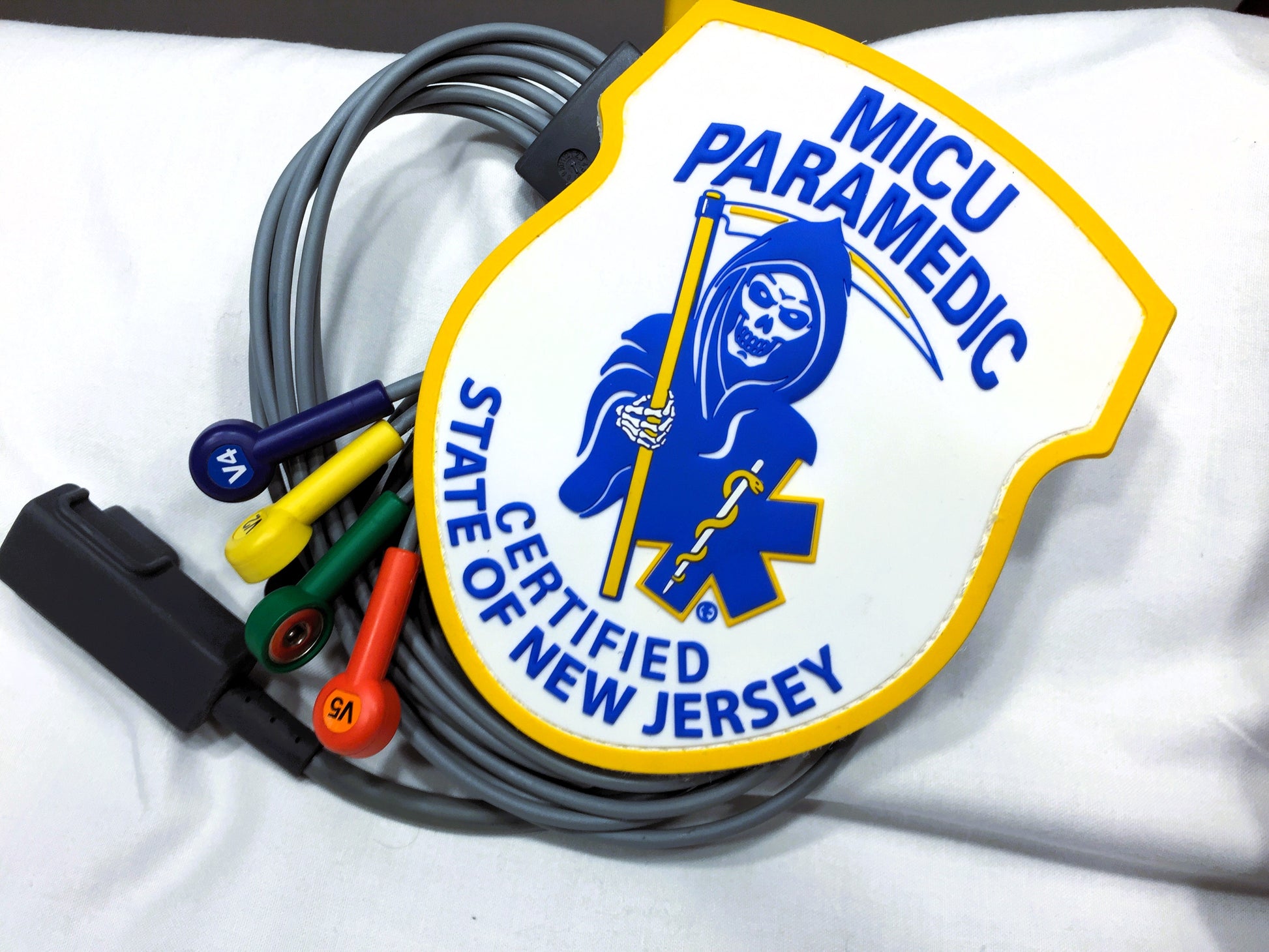 Skell City New Jersey MICU Paramedic PVC Velcro Patch up against white sheet background lying on top of 12 Lead EKG Cables