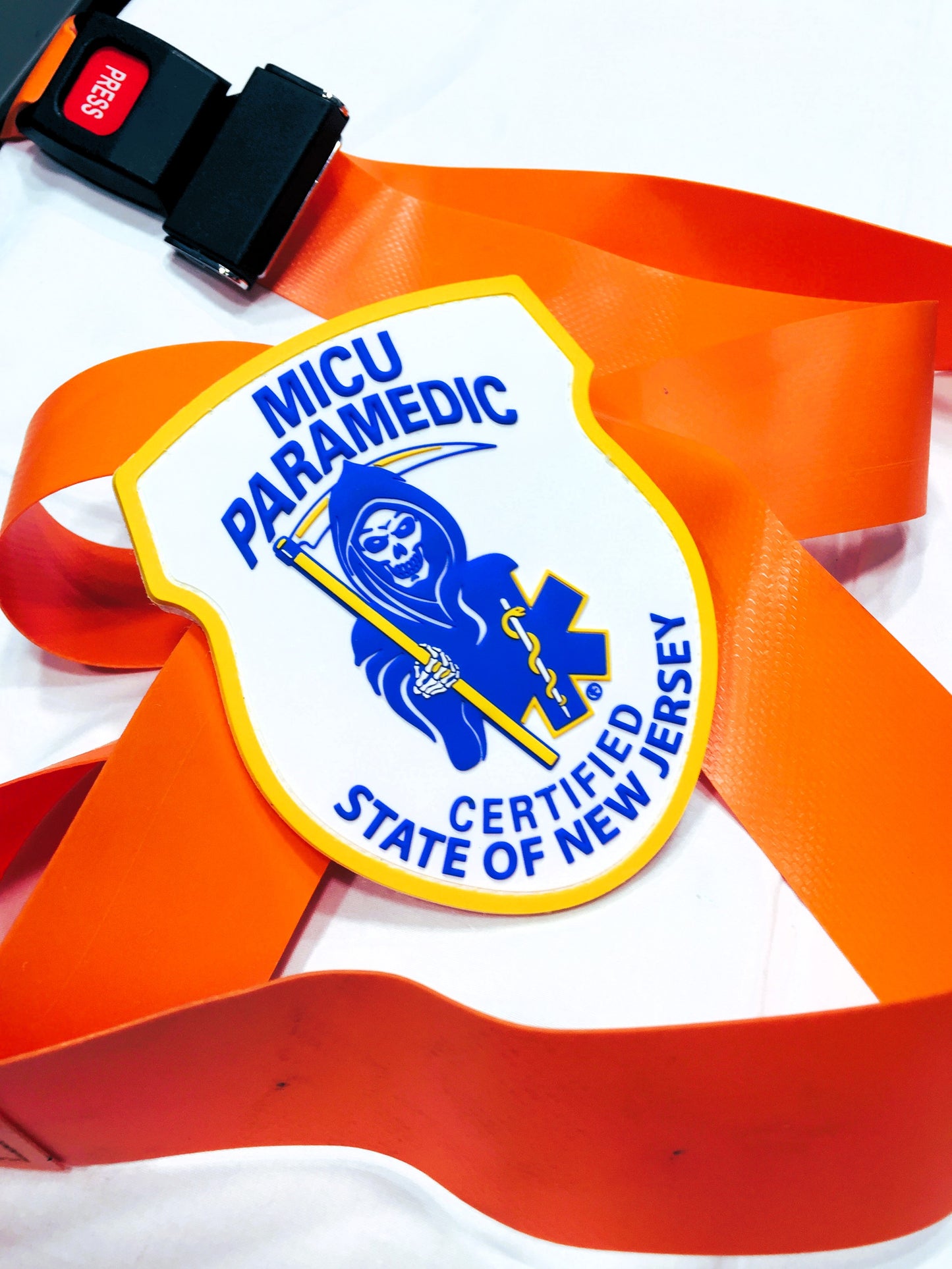 Skell City New Jersey MICU Paramedic PVC Velcro Patch up against white sheet background lying on top of orange ems stretcher straps and buckle