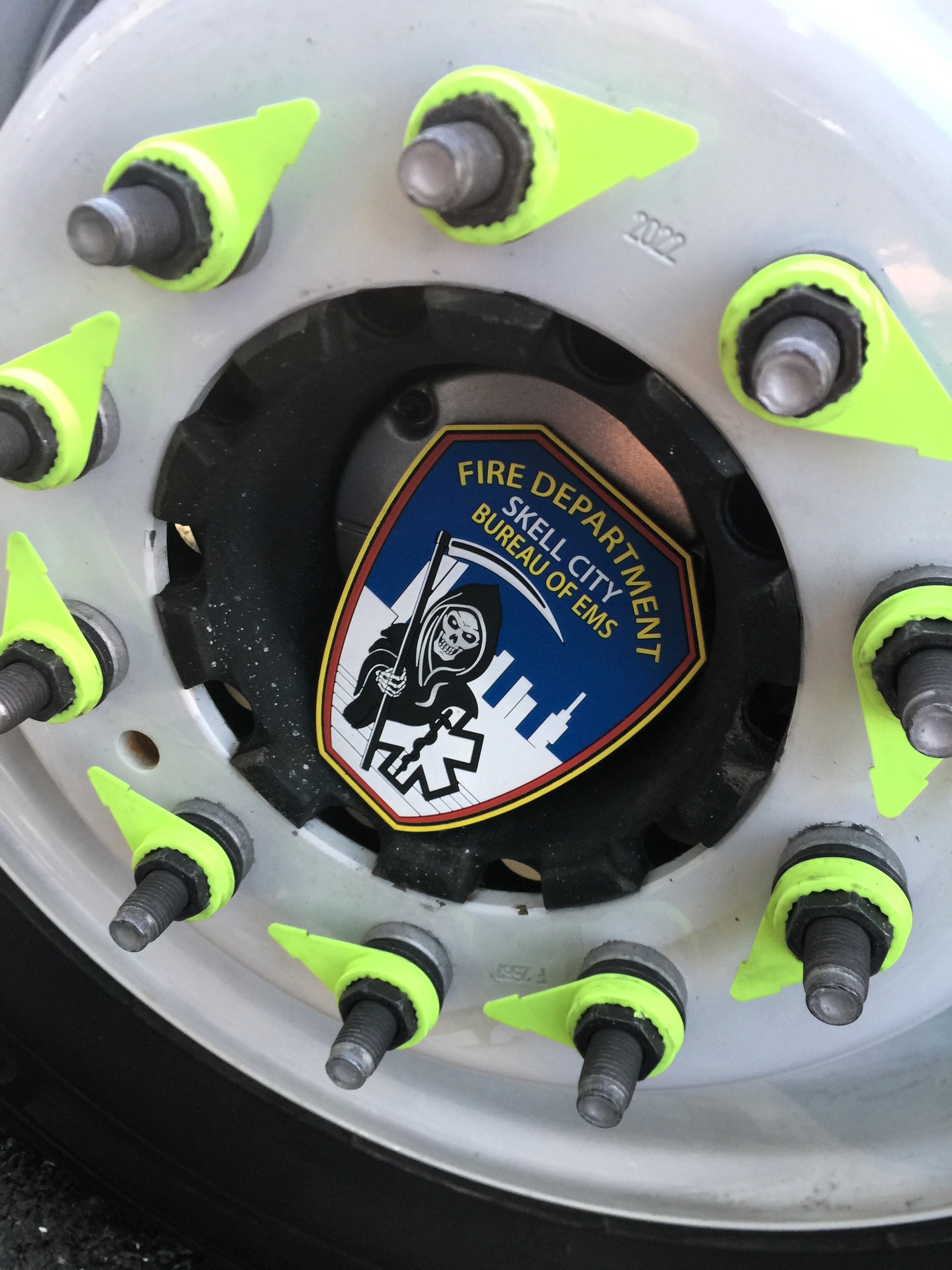 skell city EMS patch sitting inside of the spoke of an FDNY ambulance wheel.