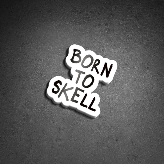 Skell City Born to skell clear sticker up against black concrete background.